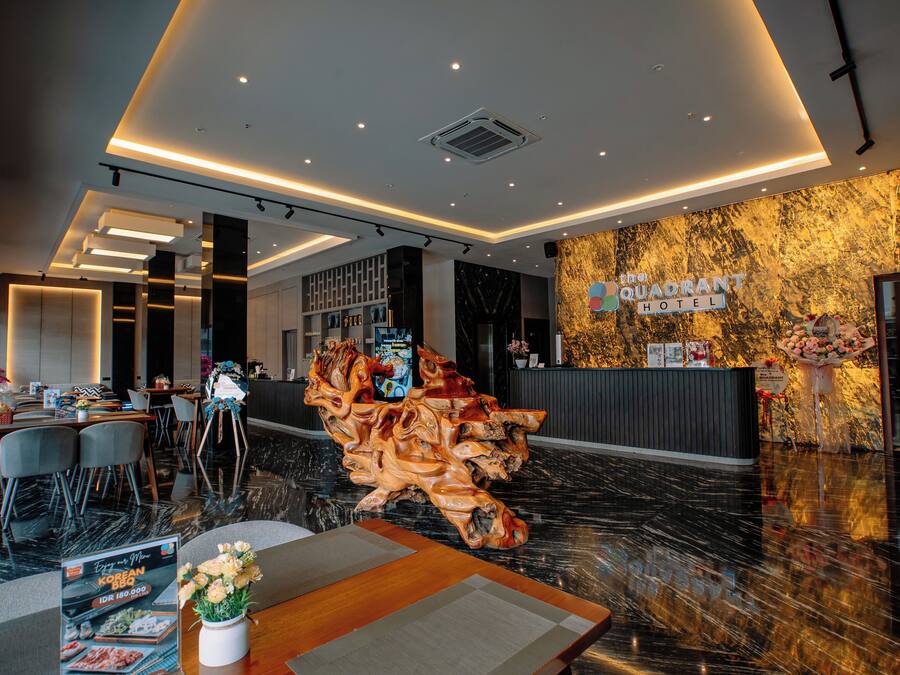 A hotel lobby with a reception desk, seating area, and a decorative wooden sculpture.