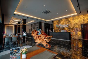 Un hall de hotel con mostrador de recepción, zona de estar y una escultura de madera decorativa.