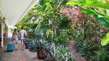 A covered walkway with lush tropical plants and an exit sign.