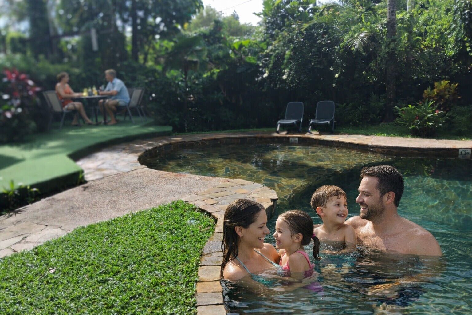 A swimming pool with a stone border and a grassy area.