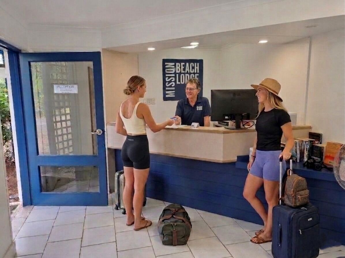 A reception desk with a sign reading 'Mission Beach Lodge,' a counter, and a computer monitor.