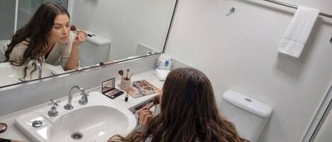 Un baño con lavamanos, espejo y artículos de aseo.