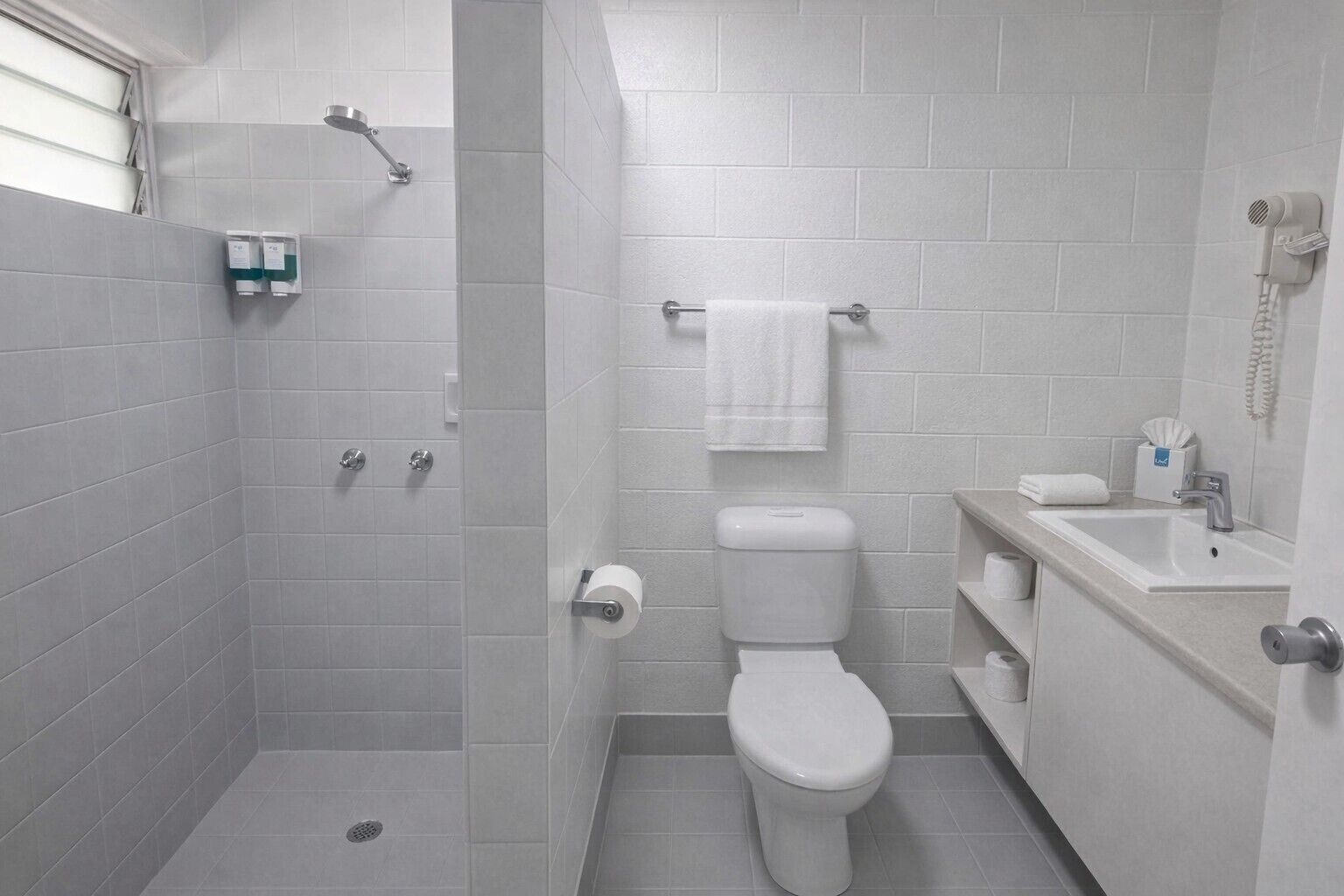 Une salle de bain moderne équipée d’une douche, de toilettes, d’un lavabo et d’un porte-serviettes.