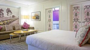 A hotel room with a bed, a sofa, a small table, and a wall with a cityscape painting. - Comic Con 2025, San Diego, Inn at the Park 32BR (San Diego)