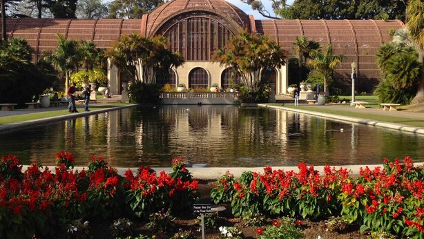A building with a dome and arched windows, surrounded by a water feature and red flowers. - Comic Con 2025, San Diego, Inn at the Park 32BR (San Diego)