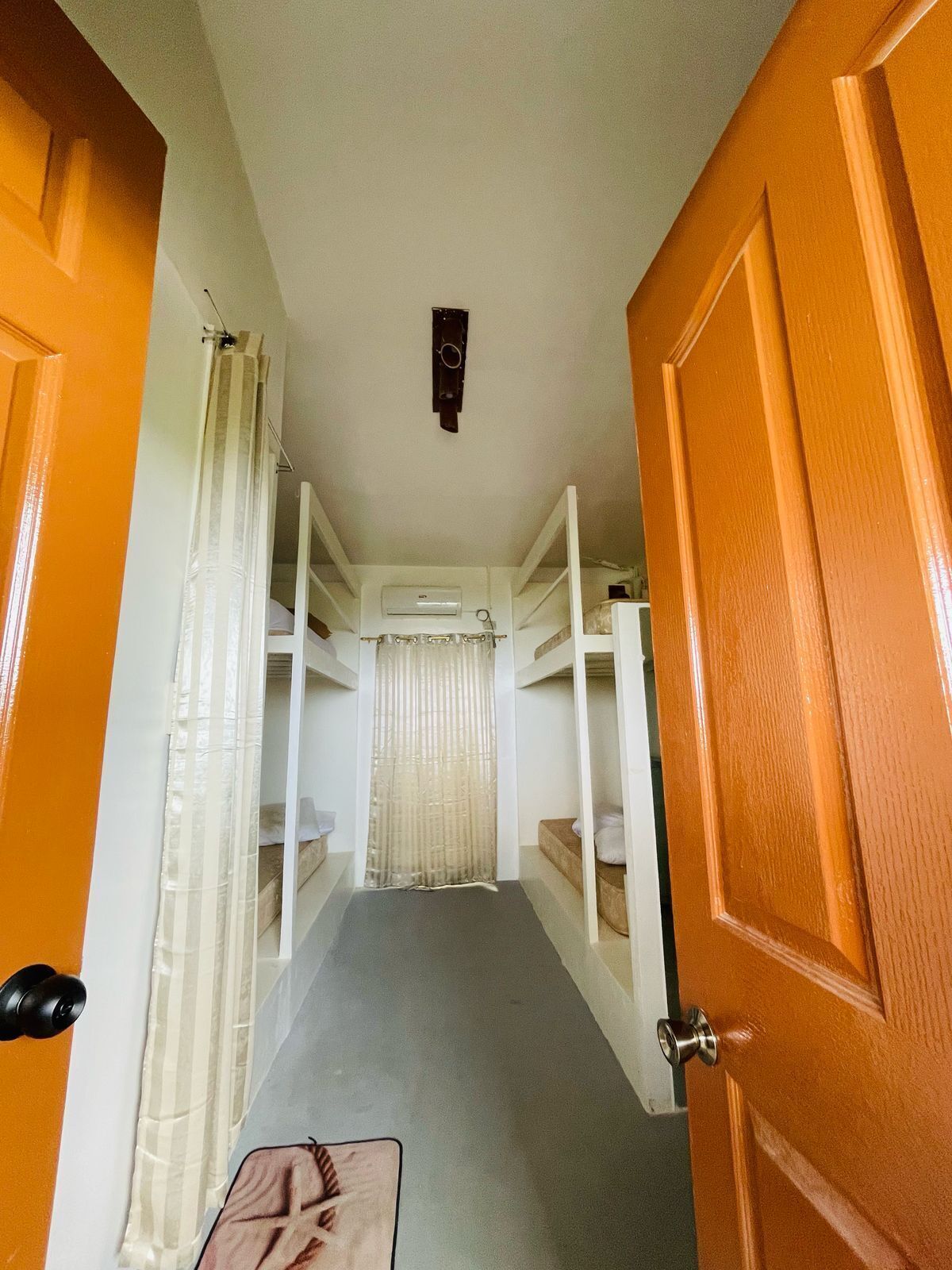 A narrow hallway with bunk beds, a door, and a curtain.