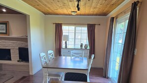 A dining area with a wooden table, chairs, a bowl of fruit, and a bottle of wine on a coaster. - Awesome Three-bedroom Retreat on 1.25 acres in Coarsegold with Trails and Views (Coarsegold)