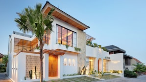 A modern two-story house with a stone facade, large windows, and a well-maintained garden. - Villa Lila (Canggu)