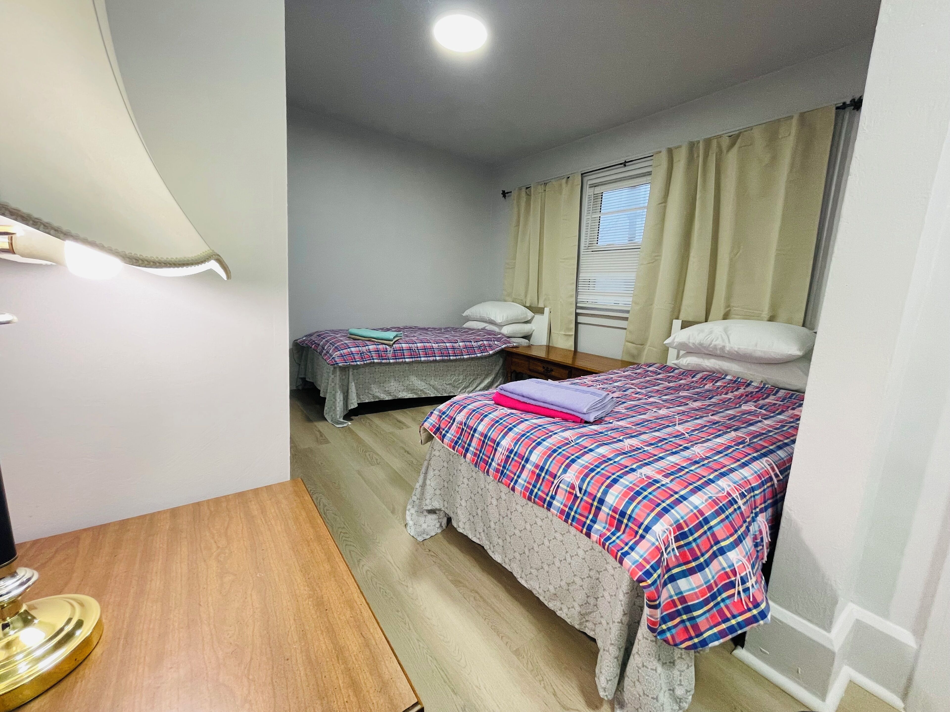 Ein Schlafzimmer mit zwei Betten, einem Schreibtisch und einem Fenster mit Vorhängen.