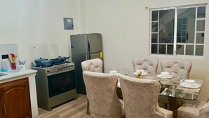 Cocina compacta con estufa a gas, refrigerador y una mesa de comedor lista para cuatro comensales.