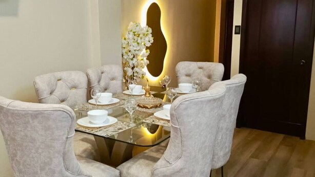 Comedor con mesa redonda dispuesta para cuatro personas, rodeada de sillas tapizadas.