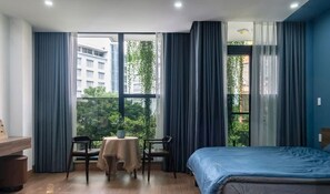 Ein Hotelzimmer mit einem Bett, einem kleinen Tisch mit Stuhl und einem Fenster mit Vorhängen.