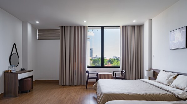 Une chambre d’hôtel moderne dotée d’un grand lit, d’un bureau avec un miroir et offrant une vue sur la ville grâce à de grandes fenêtres.