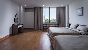 Habitación de hotel con una cama grande, un escritorio con silla, una mesita y vistas a la ciudad.