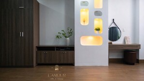 Un interior moderno con un armario de madera, una pared blanca con iluminación empotrada y una pequeña planta.