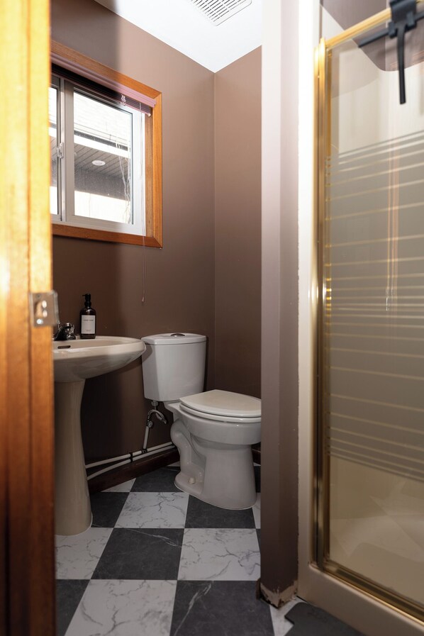 A compact bathroom with a sink, toilet, and a shower area.