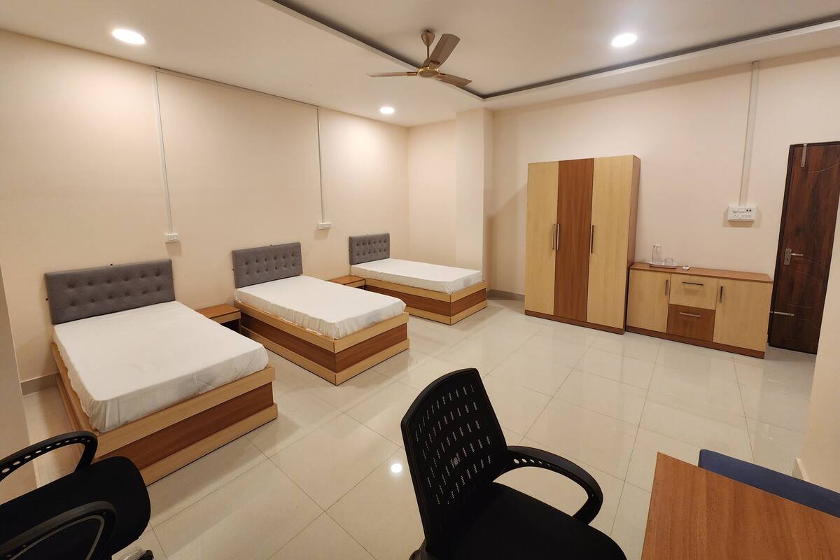 Quarto com duas camas de solteiro, um guarda-roupa, uma escrivaninha e uma cadeira.