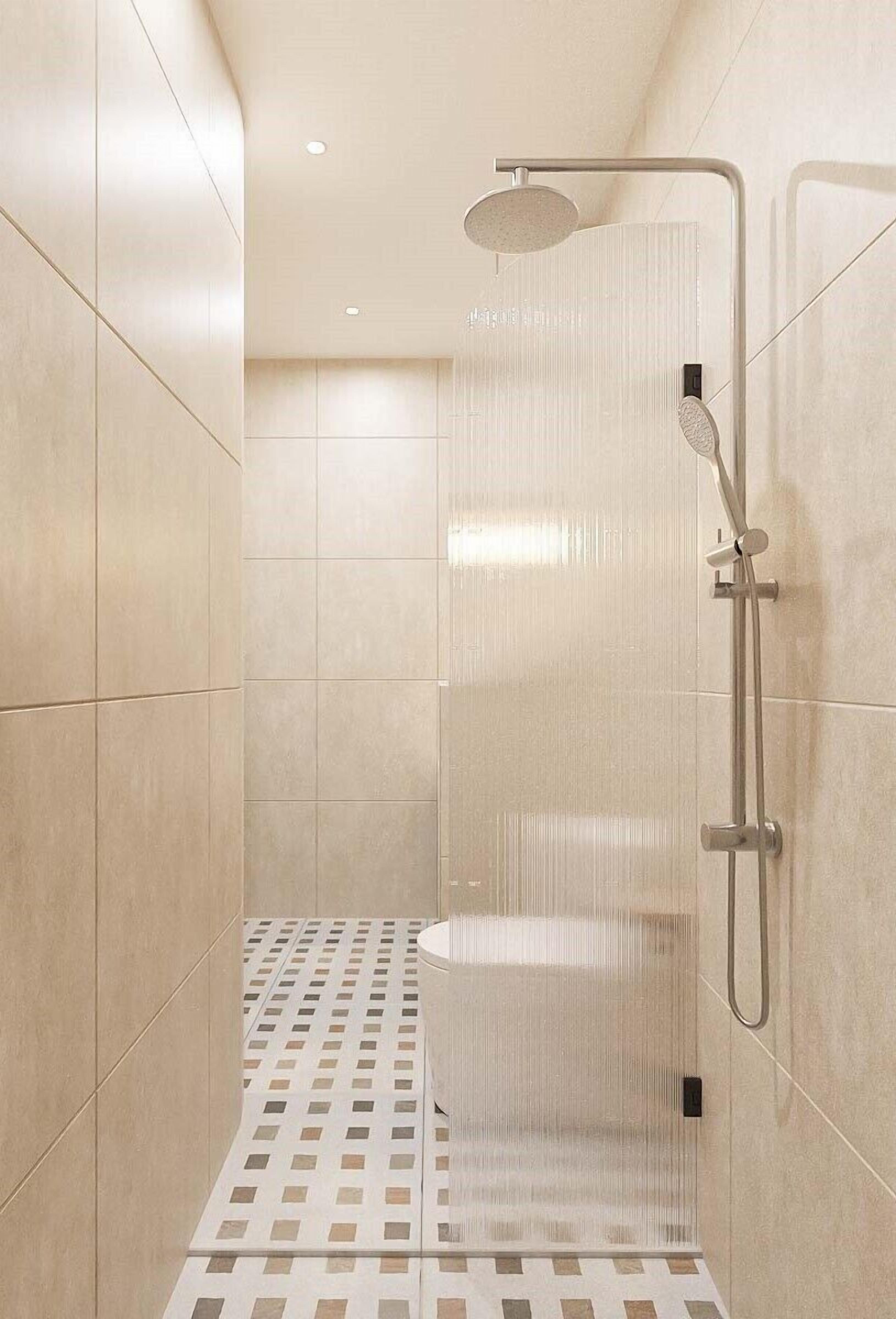 A modern shower with a handheld showerhead and a wall-mounted faucet.