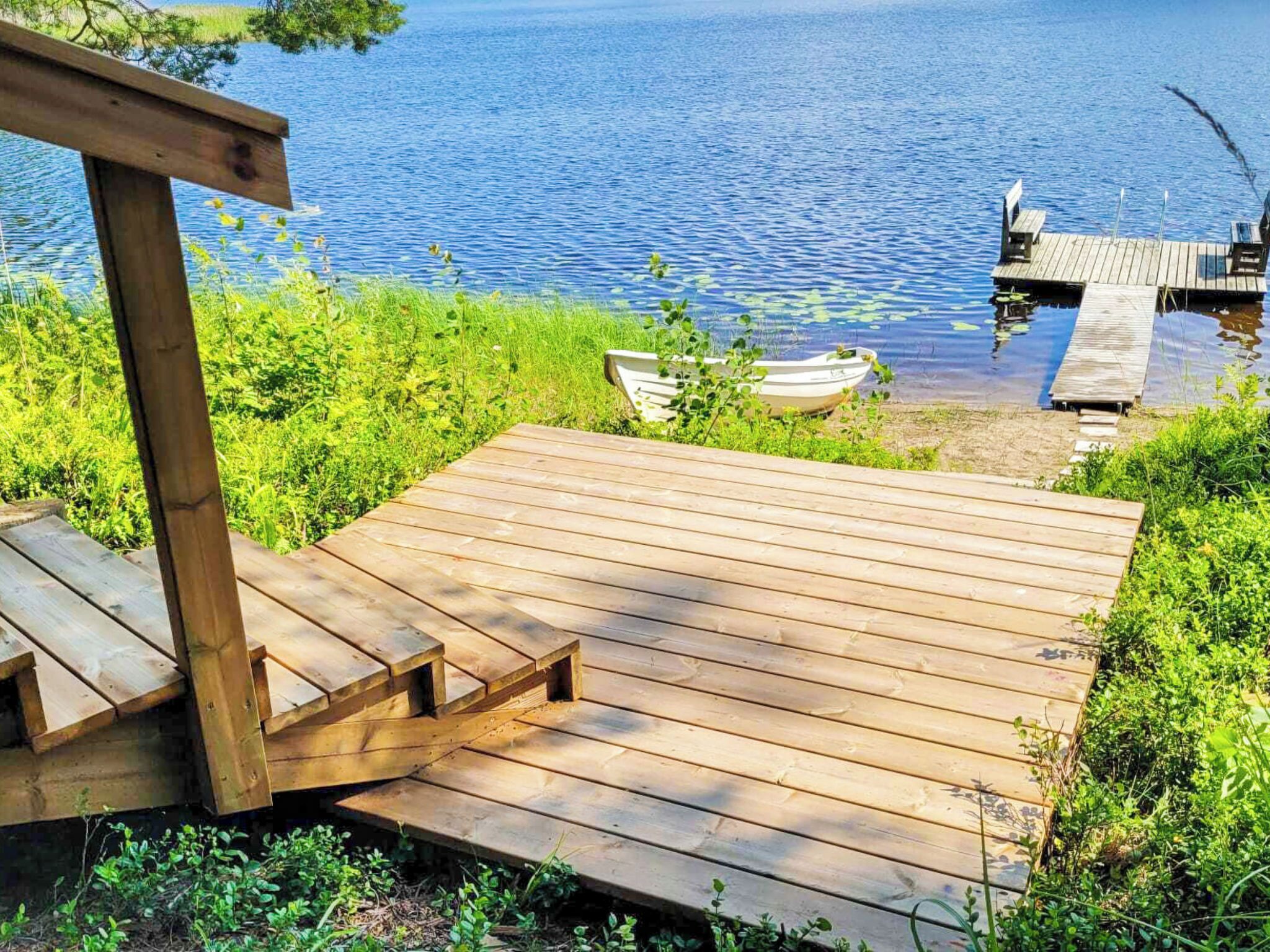 A wooden deck leading to a dock over water, with a boat and dock visible.