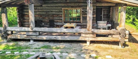 Una cabaña rústica de troncos con un porche, una mesa y sillas.