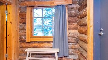 Ein rustikales Blockhaus-Interieur mit einer Bank, einem Fenster mit Vorhängen und einer Tür.