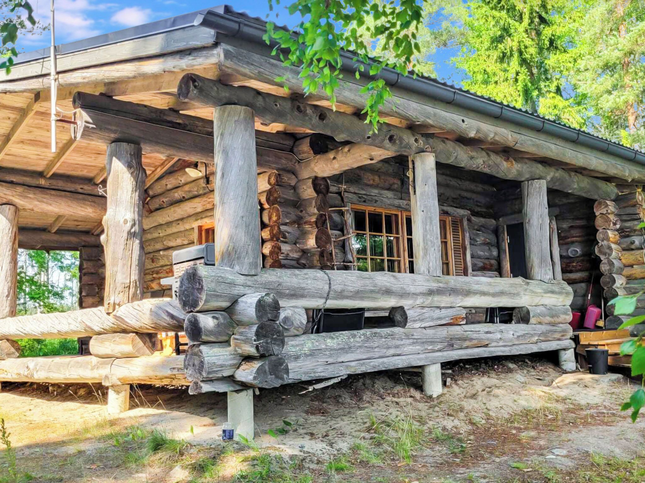 A rustic log cabin with a covered porch and a window.
