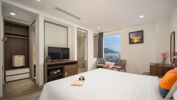 A hotel room with a large bed, a TV, a desk, and a chair.