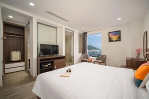 Una habitación de hotel con una cama grande, televisor, escritorio y una silla.
