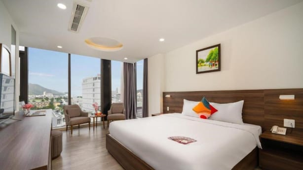 Une chambre d’hôtel moderne dotée d’un grand lit, d’un bureau et offrant une vue sur la ville.