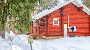 Eine rote Blockhütte mit einem Eingang, einer kleinen Veranda und einem Fenster.