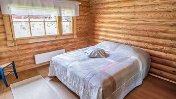 Une chambre dans une cabane en bois, avec un lit, une chaise et une fenêtre donnant sur un paysage agréable.
