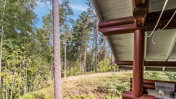 A wooden cabin with a covered porch overlooking a forested hillside. - Rustholli 1 by Interhome (Tampere)