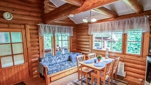 A cozy log cabin interior with a sofa, dining table, chairs, and a fireplace. - Rustholli 1 by Interhome (Tampere)