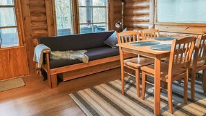A log cabin interior with a wooden dining table, chairs, a sofa, and a window with curtains. - Rustholli 1 by Interhome (Tampere)