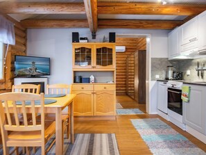 A wooden interior with a dining table, chairs, a kitchen with white cabinets, and a television displaying a lighthouse scene. - Rustholli 1 by Interhome (Tampere)