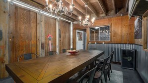Een houten eethoek met een lange tafel, stoelen en een kroonluchter.