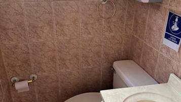 A bathroom with a toilet, sink, and hand sanitizer dispenser.