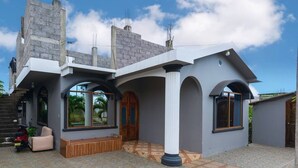 Ein modernes Haus mit einer großen Veranda, einer hölzernen Bank und einer gefliesten Terrasse.