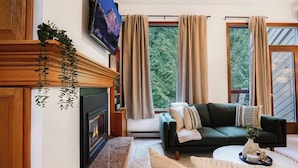 A living room with a fireplace, a sofa, a coffee table, and a TV mounted on the wall.