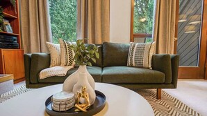 A modern living room with a green sofa, a white coffee table, and a decorative vase.
