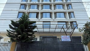 Ett hotell med flera våningar och en modern fasad, med en framträdande entré och en skylt som visar hotellets namn och kontaktuppgifter.