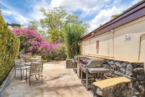 Eine Terrasse im Freien mit Grill, Stühlen und einer Steinmauer.