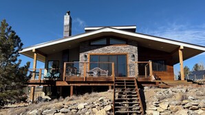 Una casa moderna con fachada de piedra, ventanas amplias y terraza de madera.