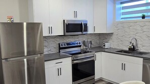 Une cuisine moderne avec des meubles blancs, des appareils en acier inoxydable et une table à manger bleue.