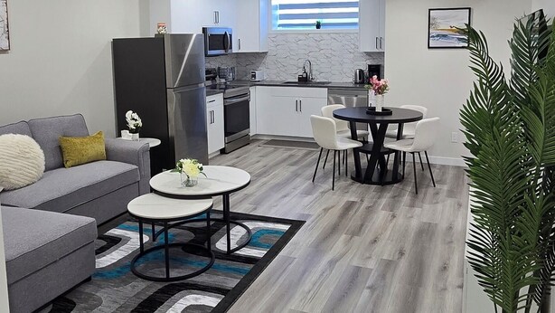 Un salon moderne avec un canapé gris, une table basse et un coin repas comprenant une table ronde et des chaises.