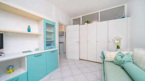 Ein kompakter Wohnbereich mit Küchenzeile, einer Couch und einem Fernseher.