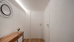 A hallway with a wooden console table, a potted orchid, a wall-mounted mirror, and a closed door. - GuestHost - Charming and quiet 30 sqm room in the heart of Bari, perfect for two people. Located on the first floor of an elegant building (access via stairs), the room is furnished with taste and attention to detail, creating a welcoming and charming at (Bari)