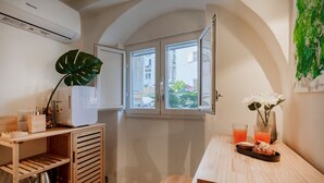 A compact kitchen with a window, wooden cabinets, a sink, and a small table with a tray of food and drinks. - GuestHost - Charming and quiet 30 sqm room in the heart of Bari, perfect for two people. Located on the first floor of an elegant building (access via stairs), the room is furnished with taste and attention to detail, creating a welcoming and charming at (Bari)