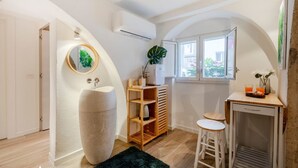 A modern kitchen with a large island, wooden shelves, and a window with a view. - GuestHost - Charming and quiet 30 sqm room in the heart of Bari, perfect for two people. Located on the first floor of an elegant building (access via stairs), the room is furnished with taste and attention to detail, creating a welcoming and charming at (Bari)