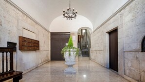 A marble-floored hallway with a large urn, a bench, and a chandelier. - GuestHost - Charming and quiet 30 sqm room in the heart of Bari, perfect for two people. Located on the first floor of an elegant building (access via stairs), the room is furnished with taste and attention to detail, creating a welcoming and charming at (Bari)